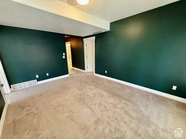 Lower level Den featuring wall-to-wall carpeting, deep-toned accent walls, white-paneled interior door, and glass-paneled French doors with integrated blinds that lead to covered patio