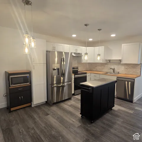 Kitchen featuring white shaker-style cabinetry, wood-finish countertops, stainless steel appliances, a tile backsplash, and wood-finish flooring