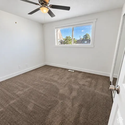 Neutral-toned wall-to-wall carpeting, single-pane window with white trim, and a ceiling fan with integrated lighting
