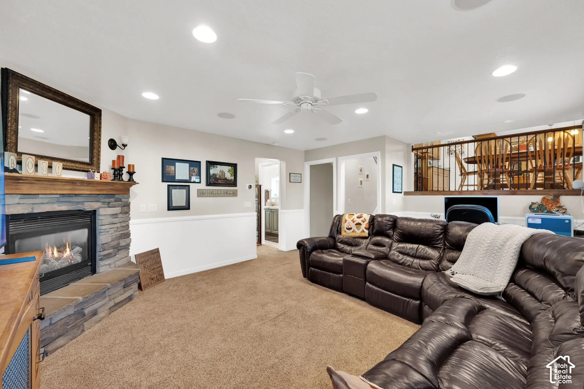 Living area featuring a stone-clad fireplace with a wood mantel, recessed lighting, a ceiling fan, and decorative chair rail molding