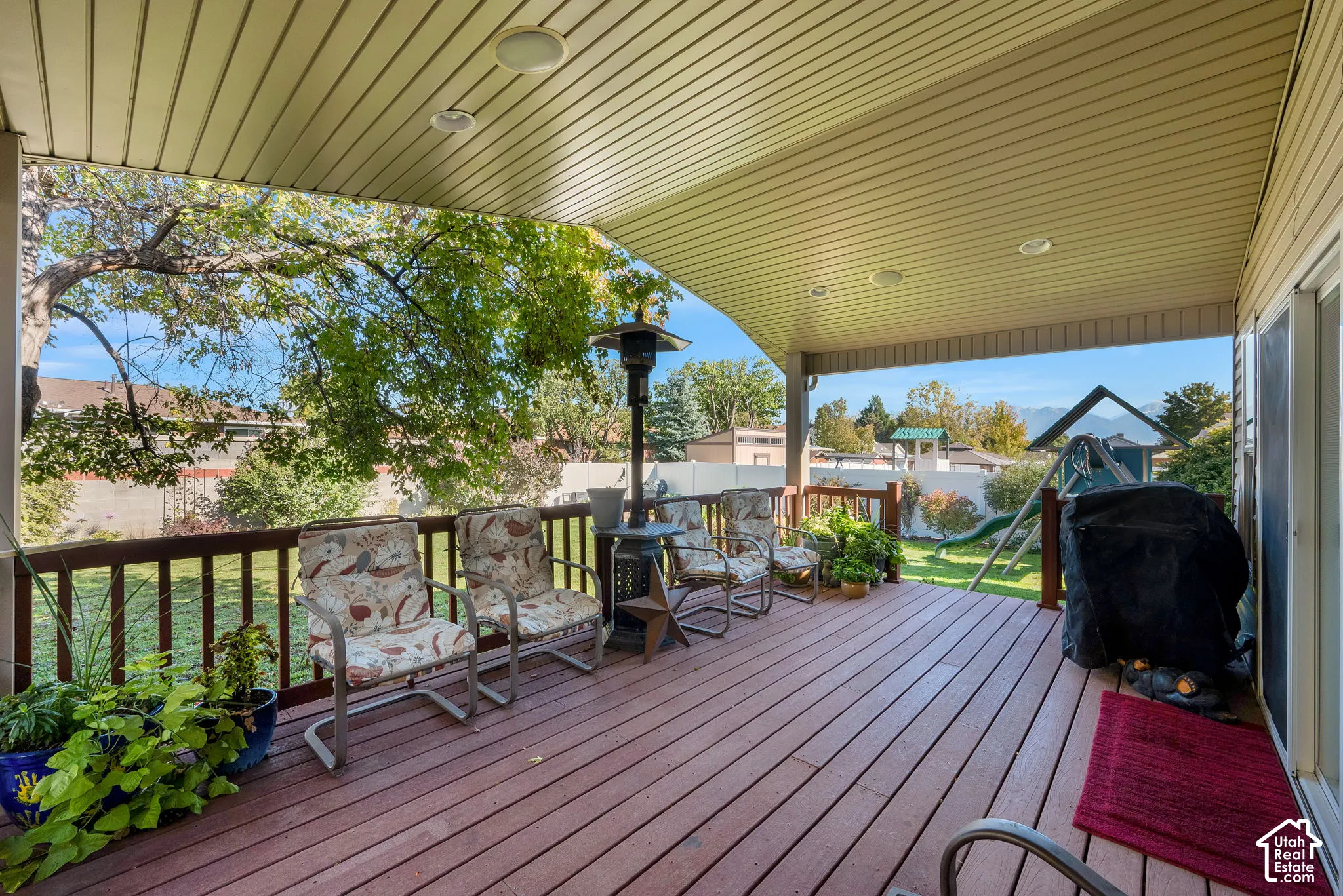 Covered exterior deck featuring composite decking, recessed lighting, and wooden railings