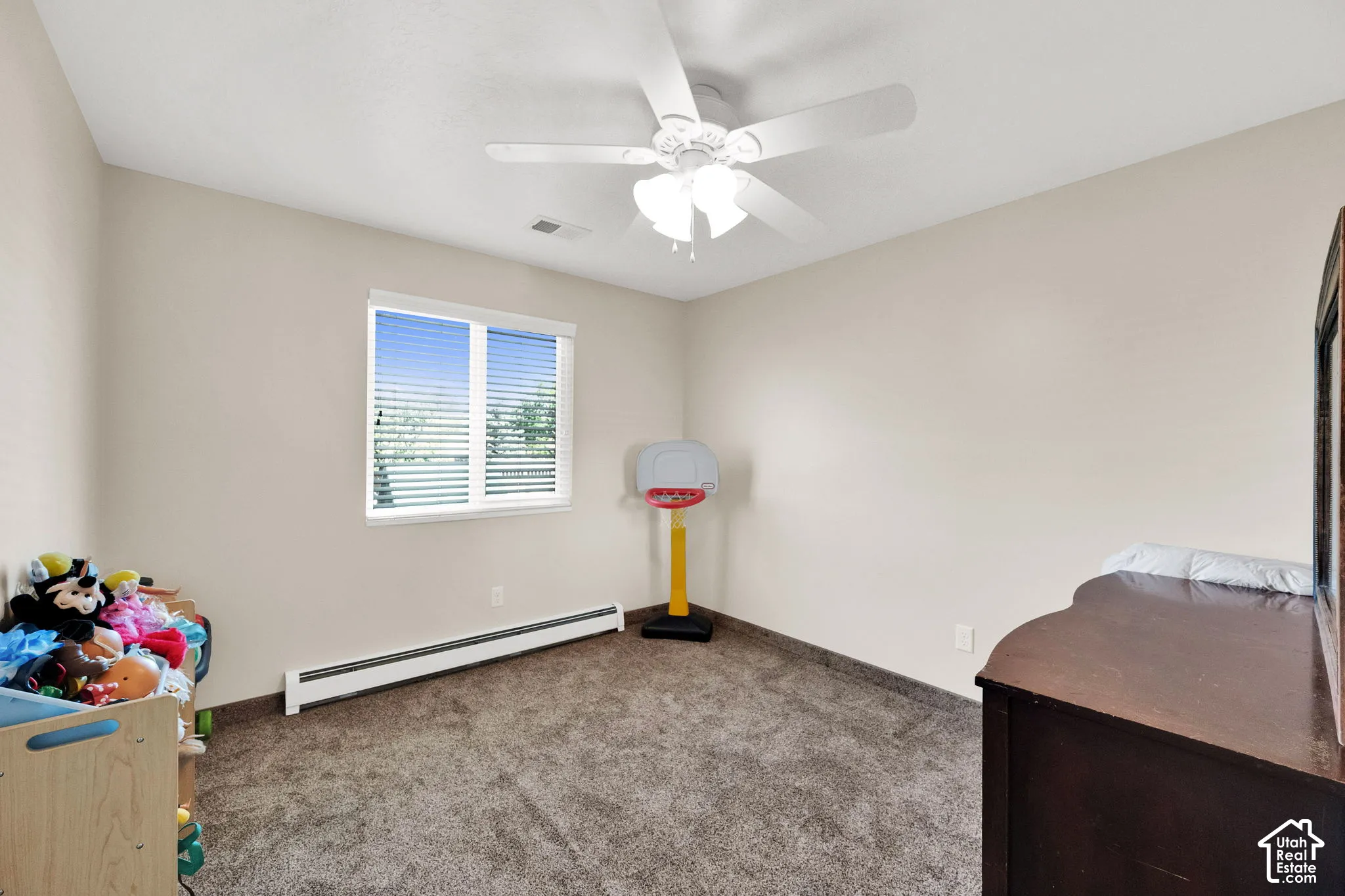 Neutral-toned walls featuring a ceiling-mounted light fixture with an integrated fan and a window with horizontal blinds over wall-to-wall carpeting