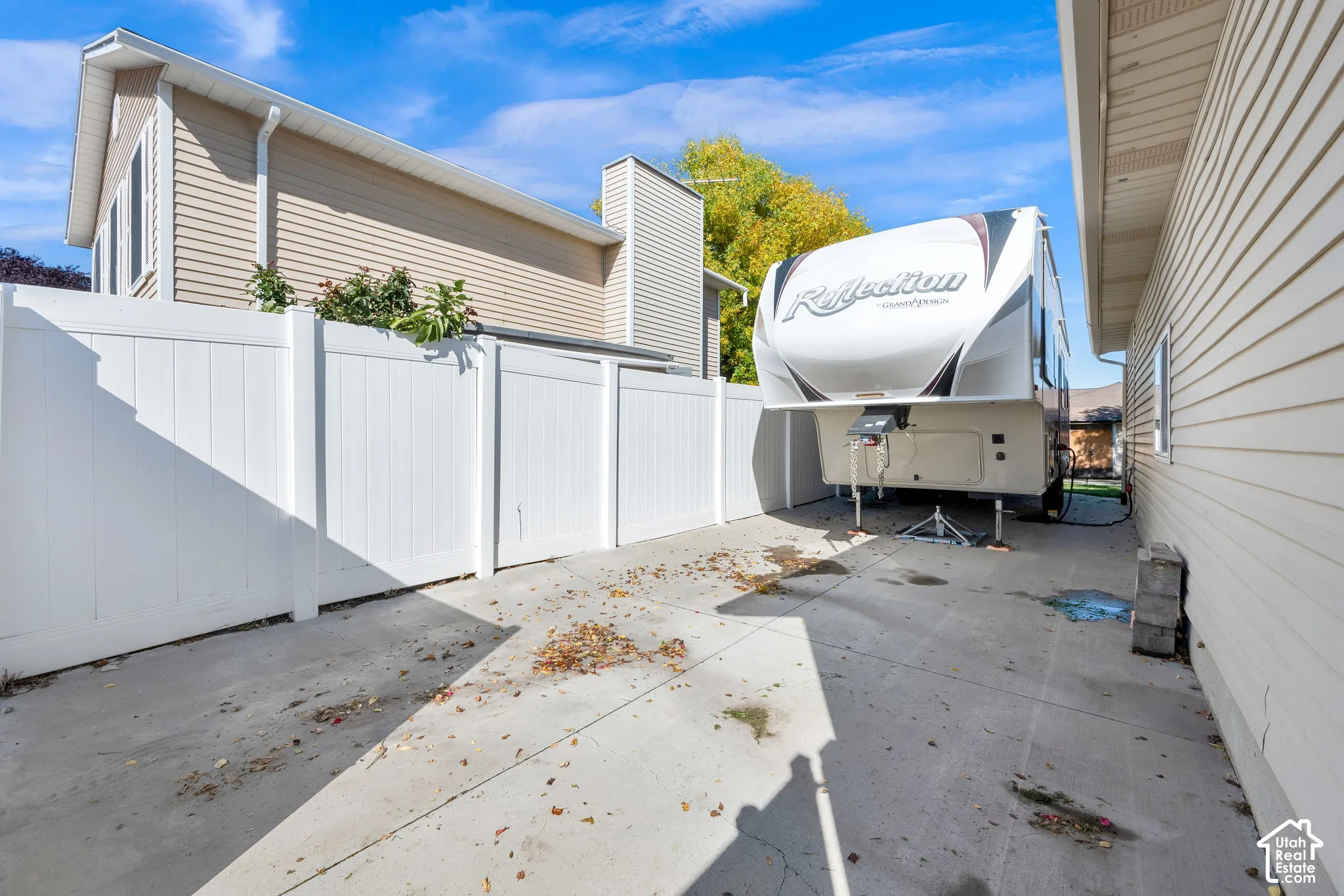 Concrete side yard featuring a white vinyl privacy fence and beige horizontal vinyl siding