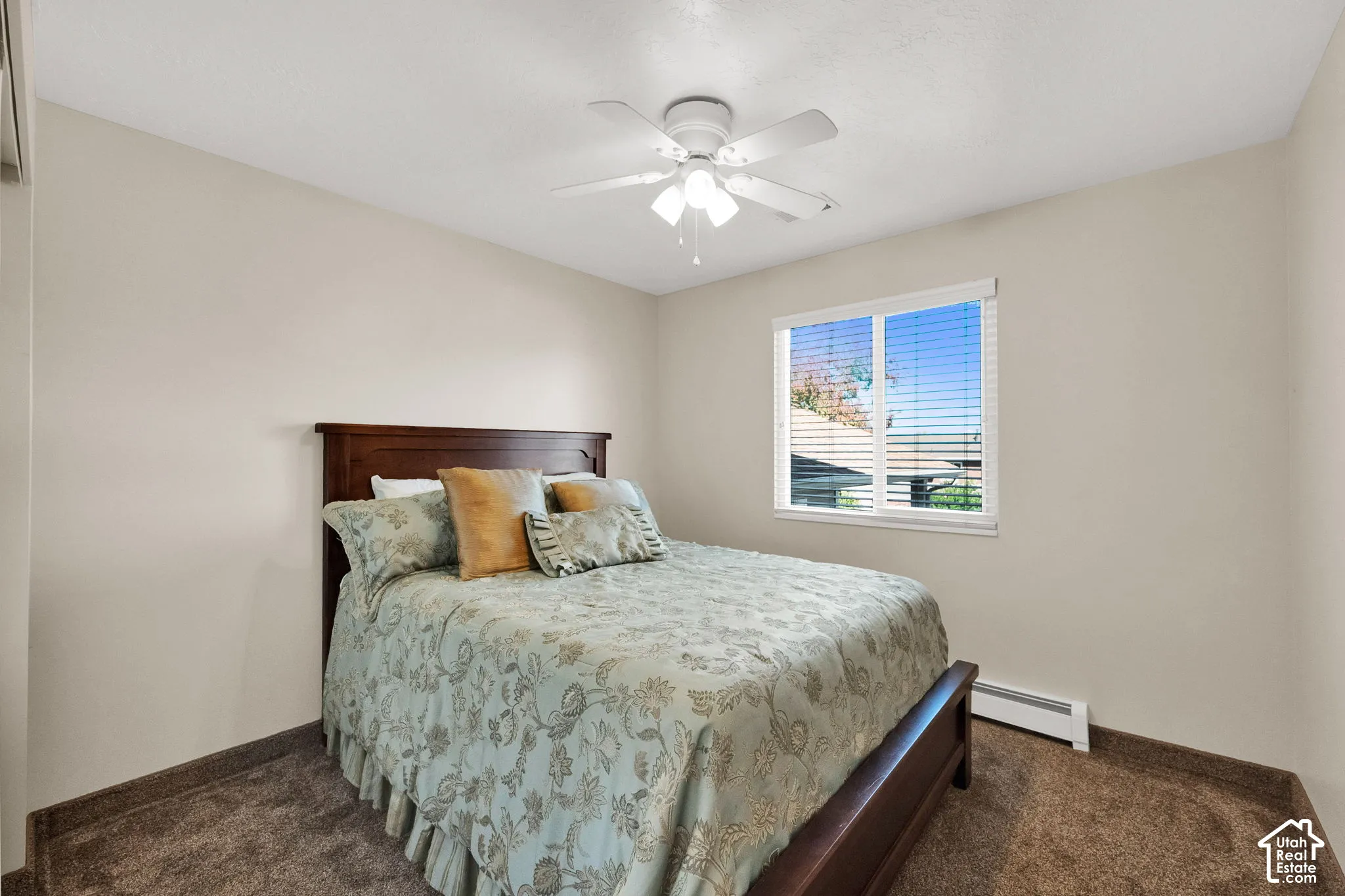 Neutral-toned bedroom featuring carpeted flooring, a white ceiling fan with integrated lighting, and horizontal window blinds