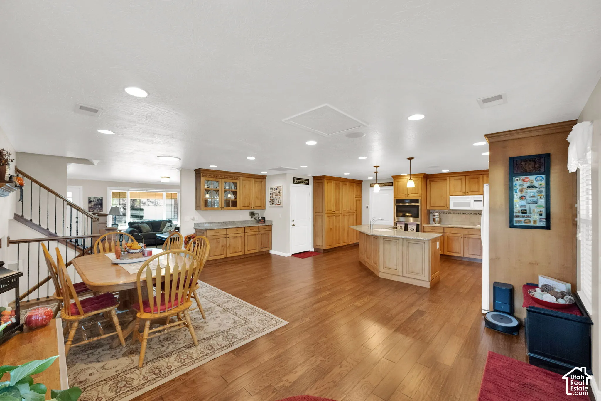 Kitchen featuring wood cabinetry, an expansive central island, recessed lighting, and wood-finish flooring