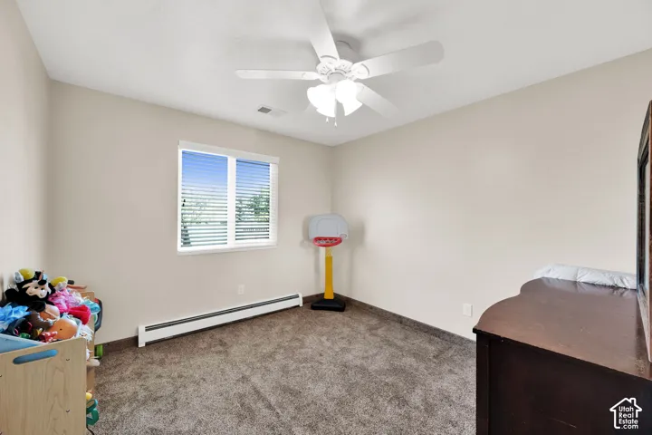 Neutral-toned walls featuring a ceiling-mounted light fixture with an integrated fan and a window with horizontal blinds over wall-to-wall carpeting