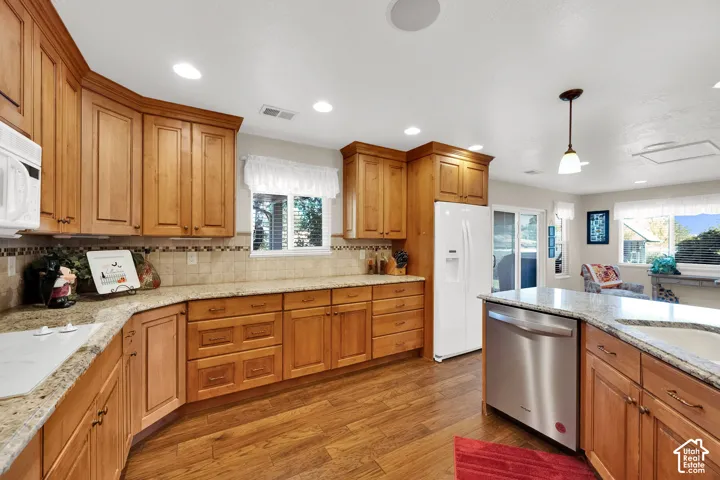 Kitchen featuring natural wood cabinetry, stone-surface countertops, tile backsplash, recessed lighting, and wood-finish flooring