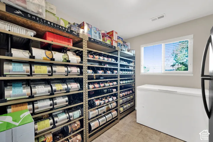 Storage room featuring multi-level metal industrial shelving units, a horizontal sliding window, and tile flooring