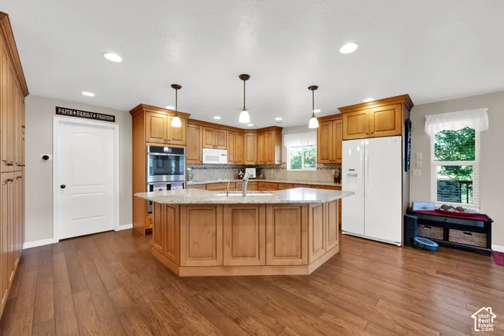 Kitchen featuring wood cabinetry, a central island with a stone-composite countertop, recessed lighting, and wood-finish flooring