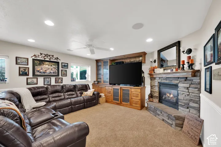 Floor-to-ceiling stone fireplace, custom wood built-in cabinetry, recessed lighting, and a ceiling fan