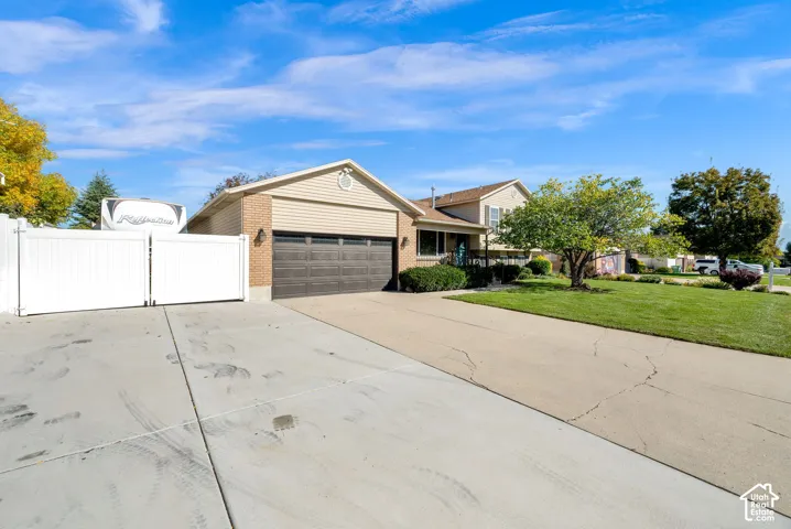 Exterior featuring horizontal siding, a two-car garage, an expansive concrete driveway, and white vinyl privacy fencing