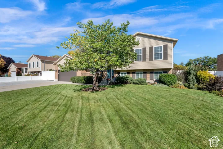 Split-level residence featuring a brick and vinyl siding exterior, an attached garage, and a manicured front lawn