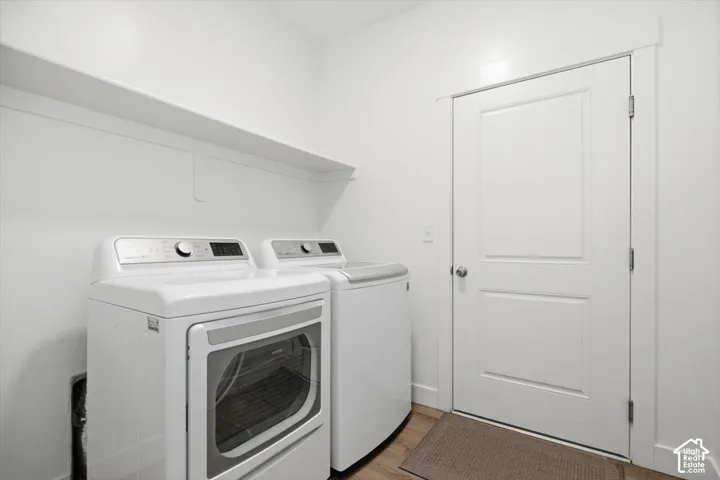 Dedicated laundry area featuring wood-finish flooring, a white paneled door, and integrated shelving