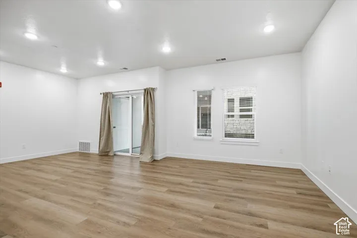 Open-concept room featuring neutral wall tones, wood-finish flooring, recessed lighting, double-pane windows, and sliding glass doors