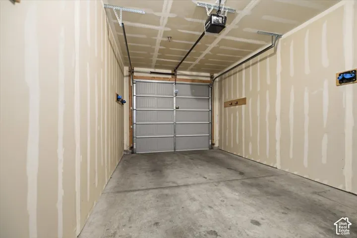 Enclosed garage featuring concrete flooring, an overhead sectional door, and an automatic garage door opener