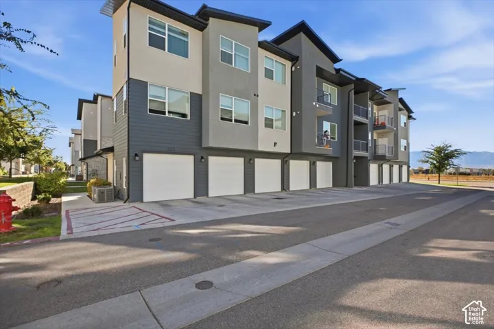 Multi-story exterior featuring horizontal lap siding, stucco finishes, attached garages, and private balconies with metal railings