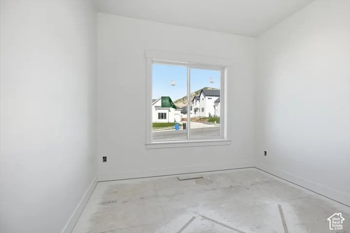 Neutral-toned interior space featuring a slider window with white trim, smooth-finish walls, and a concrete subfloor