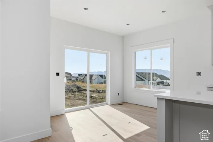 Bright interior featuring wood-finish flooring, recessed lighting, sliding glass door, single-hung window, and mountain backdrop