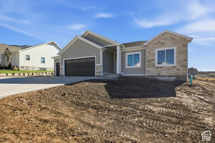Exterior facade featuring vertical siding and stone veneer, concrete driveway, and attached garage