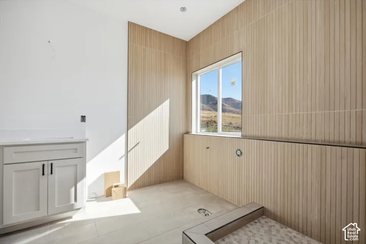 Vertical slatted wall tile, light-toned large-format floor tile, custom vanity cabinet with light-toned countertop, and recessed ceiling lighting