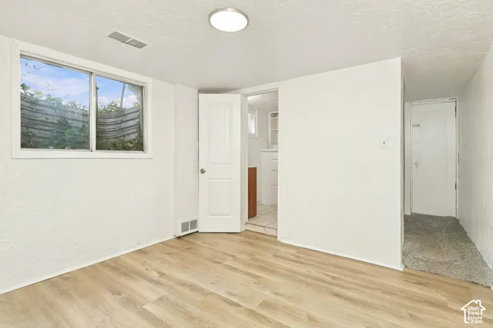 Interior space featuring wood-finish flooring, a flush-mount ceiling light fixture, a horizontal sliding window with an integrated egress well, and a multi-panel door