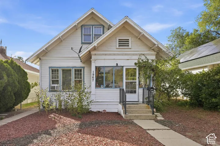 Cottage-style exterior featuring horizontal siding, decorative gable trim, a covered front porch, and multi-pane windows