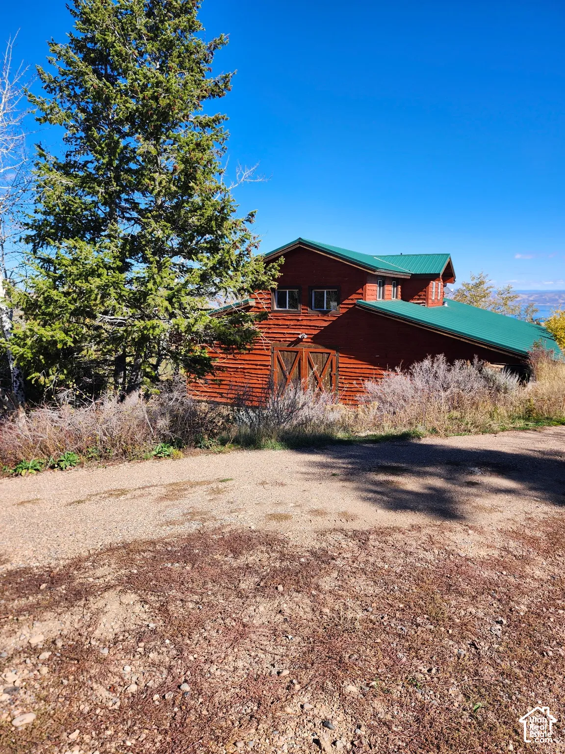 Rustic log cabin with distinctive red-stained wood siding and green metal roof accents
