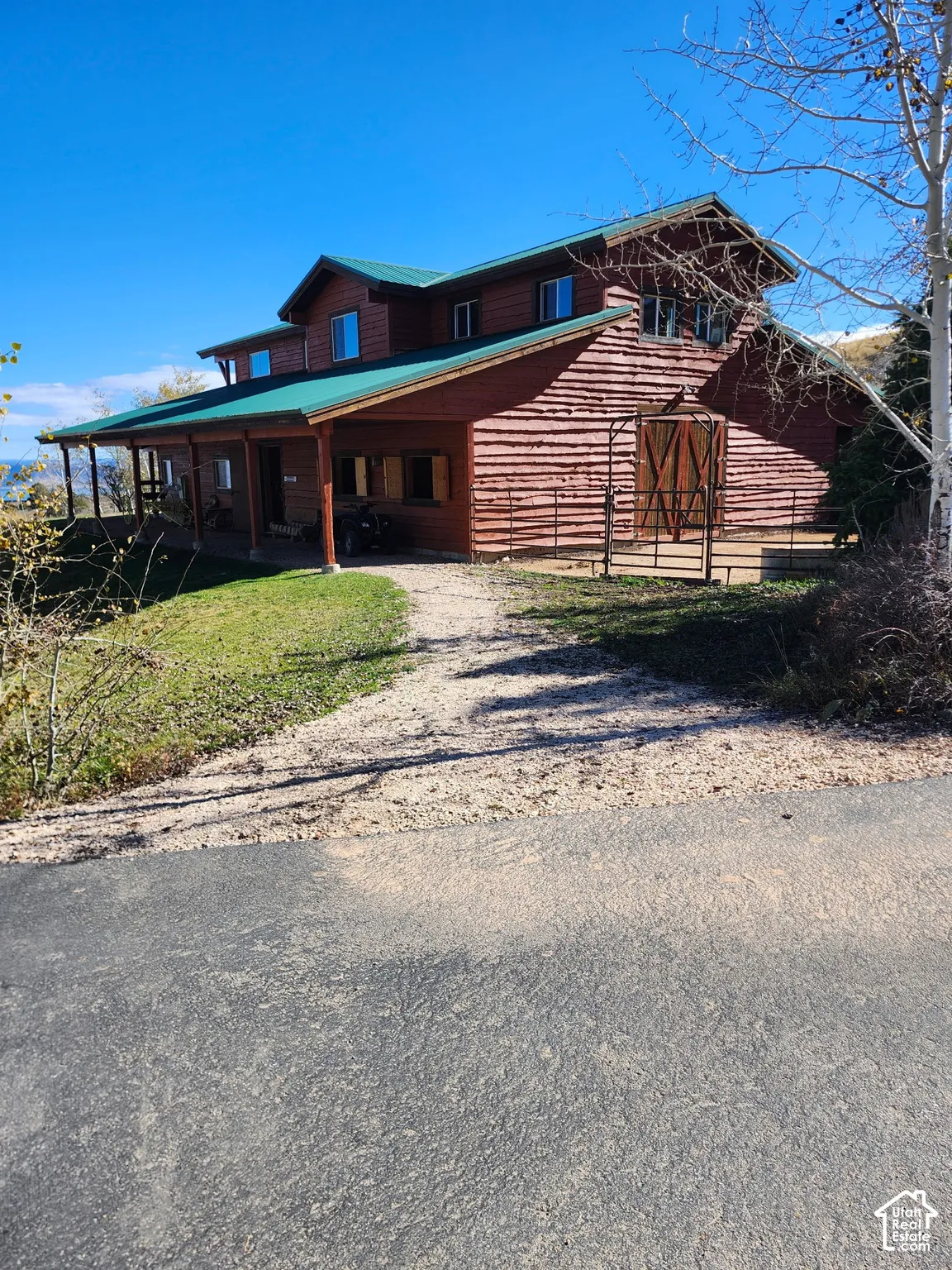 Two-story log cabin exterior featuring a metal roof, wraparound covered porch, and integrated barn-style doors