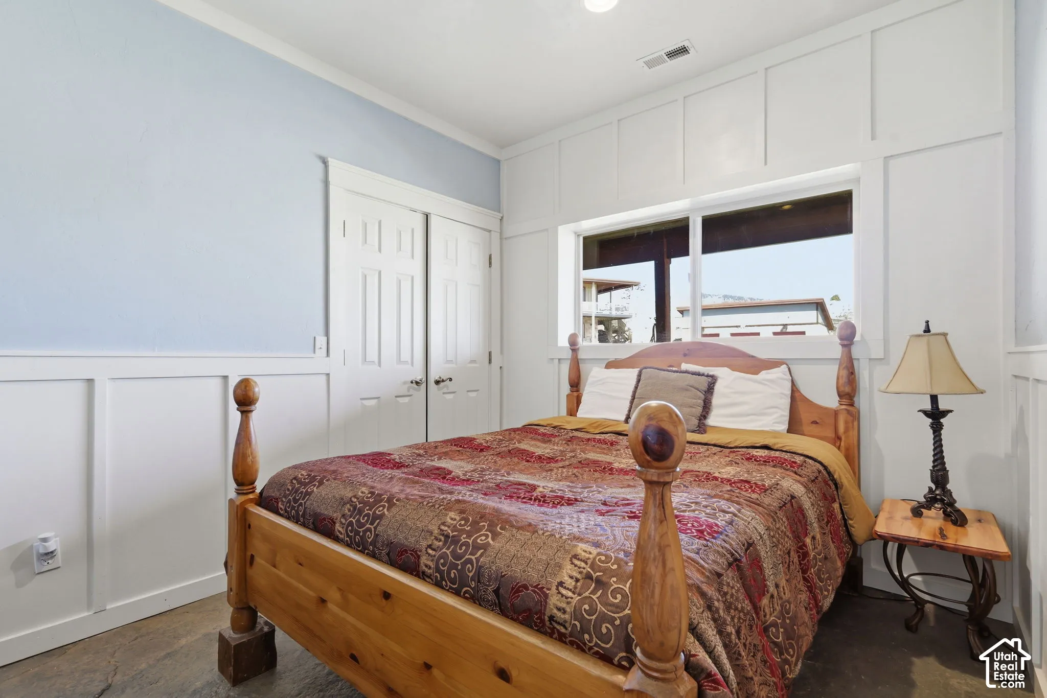 Bedroom featuring floor-to-ceiling white board-and-batten wall detailing, dual-panel closet doors, and large sliding window