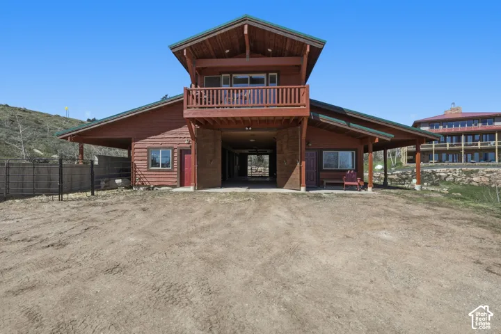 Rustic wood-sided residence featuring a distinctive peaked roofline with covered front porch, multiple windows for natural light, and expansive overhanging eaves