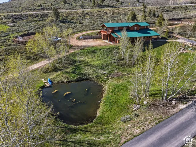 Multi-level log-style residence featuring a metal roof, private on-site pond, and expansive grounds with mature aspen trees