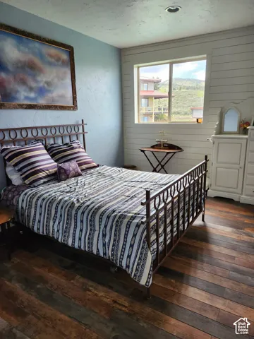 Bedroom featuring wide-plank wood-finish flooring, horizontal shiplap wall detailing, recessed lighting, and a sliding window with mountain scenery