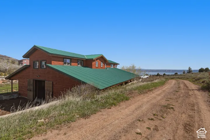 Rustic wood-sided structure featuring a green metal roof, multiple windows, and sliding barn-style doors