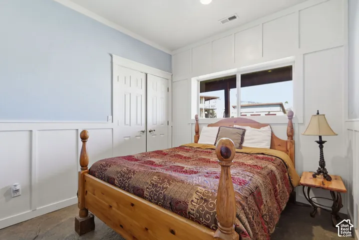 Bedroom featuring floor-to-ceiling white board-and-batten wall detailing, dual-panel closet doors, and large sliding window