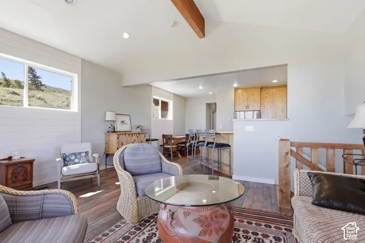 Vaulted ceiling featuring an exposed wood beam, horizontal wall paneling, wood-finish flooring, recessed lighting, and wooden stair railing