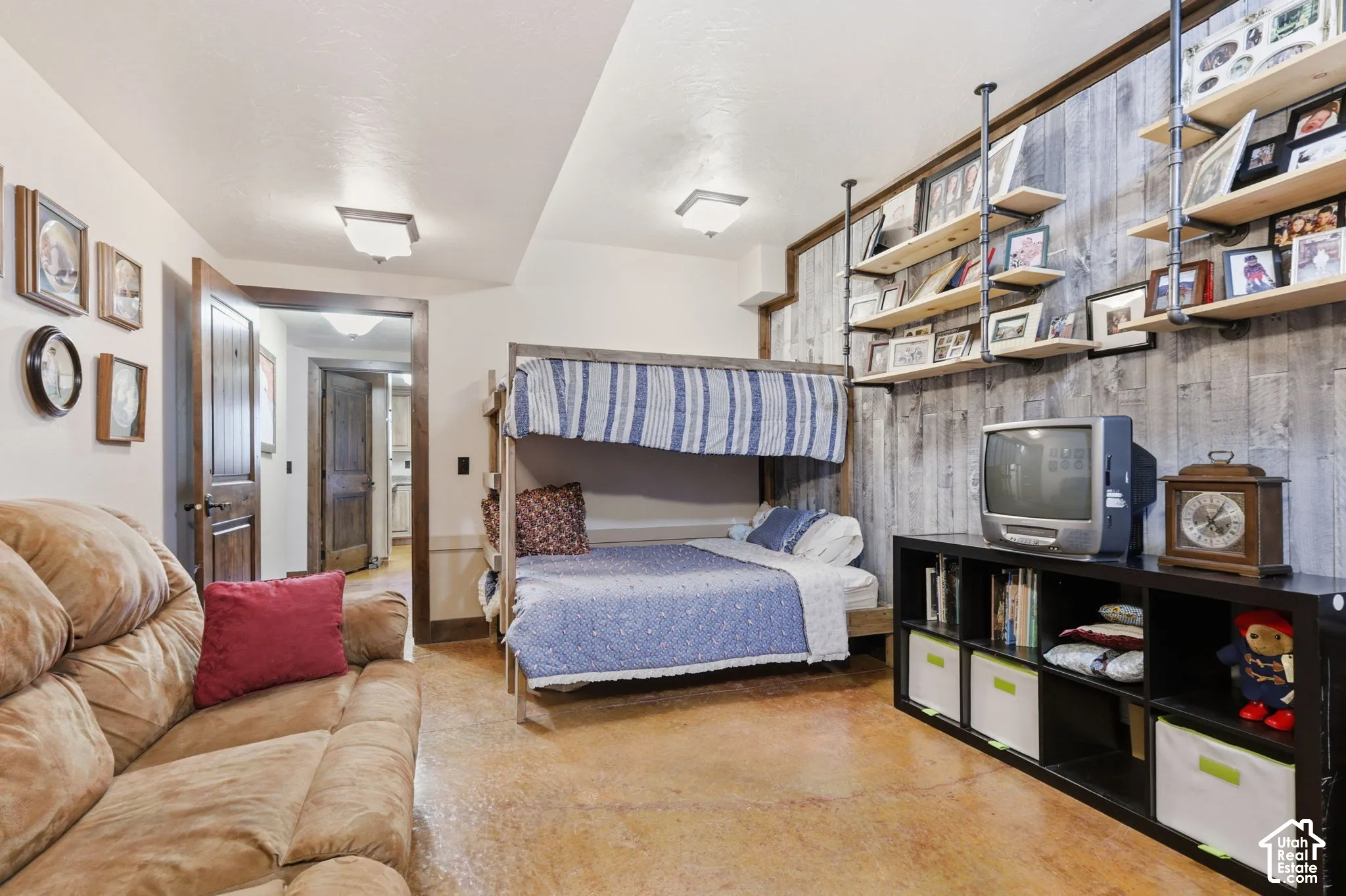 Concrete flooring, vertical wood-plank wall finish, and industrial-style metal pipe shelving