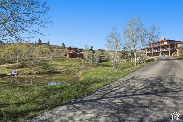 Expansive grounds featuring a private pond, paved driveway, multi-level structures with wood siding, and mature trees