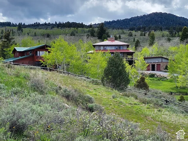Multi-structure property featuring wood siding, metal roofing, brick masonry accents, and expansive mountain scenery