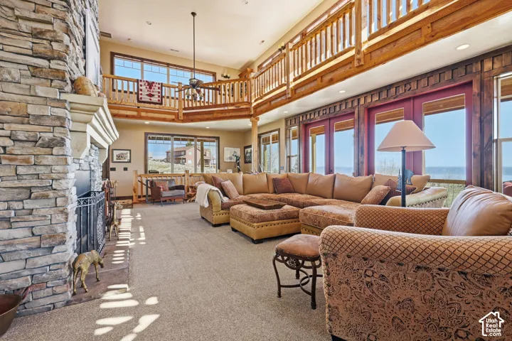 Floor-to-ceiling stone fireplace, vaulted ceilings, wooden balcony railing, large picture windows, and recessed lighting