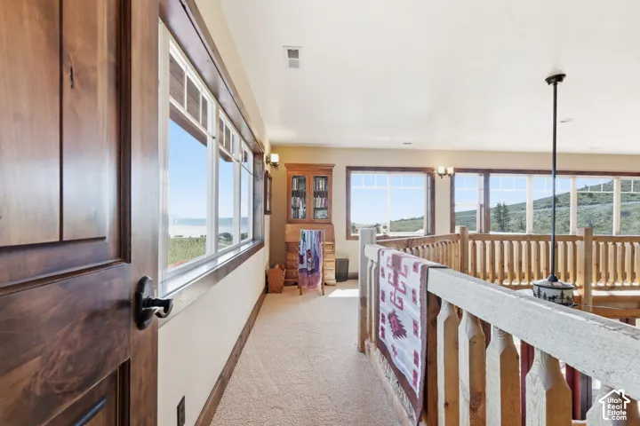 Interior hallway featuring expansive windows with mountain scenery, wood-framed windows, a built-in wooden cabinet, and a wooden balustrade