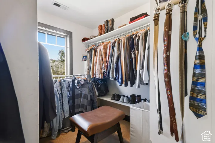 Walk-in closet featuring tiered shelving, hanging rods, and a window with exterior scenery