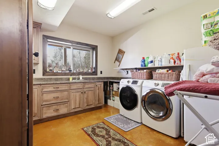 Laundry area featuring stained concrete flooring, extensive wood-finish cabinetry, an integrated stone-composite countertop with a drop-in sink, and a horizontal wall-mounted shelf