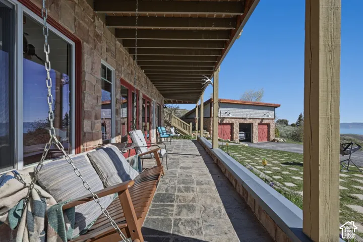 Covered porch featuring natural stone masonry, flagstone flooring, exposed beam ceiling, and pillar supports