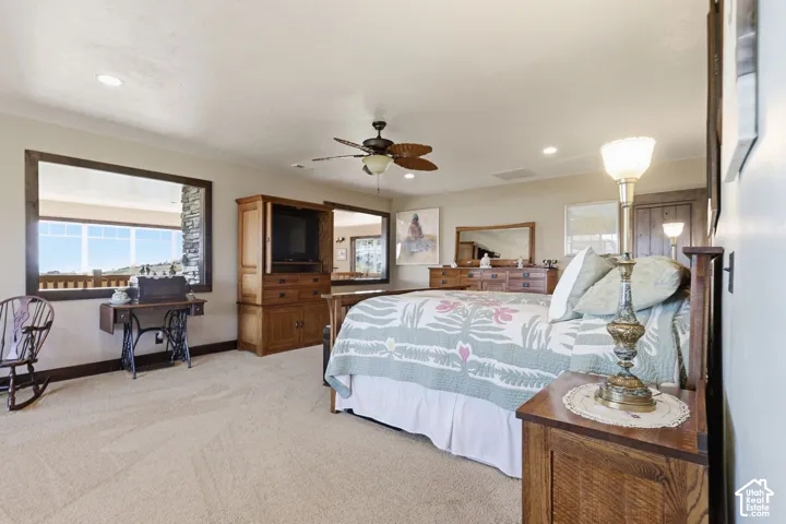 Spacious room featuring neutral carpeting, recessed lighting, a ceiling fan, and large picture windows framed in dark wood trim