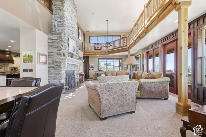 Floor-to-ceiling stone fireplace, vaulted ceilings, wooden balcony railing, custom wood support columns, and large windows