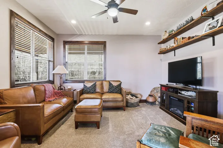 Living space featuring wood-cased windows, recessed lighting, ceiling fan, and wall-mounted floating shelves