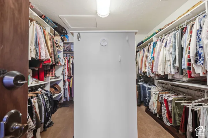 Walk-in closet featuring multi-tiered built-in shelving, dual hanging racks, a centralized partition with integrated hooks, and overhead lighting