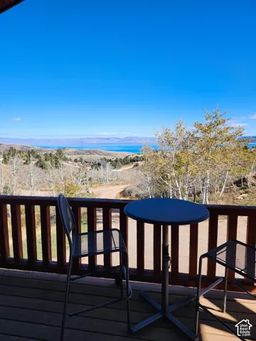 Elevated wooden deck featuring a horizontal railing and expansive, elevated landscape scenery including a body of water and mountain terrain