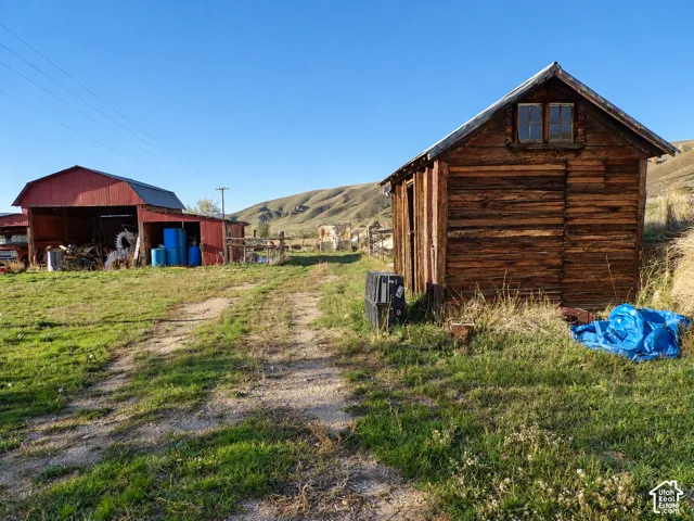 Rural acreage featuring a rustic wood-plank outbuilding and a detached red barn with open bays