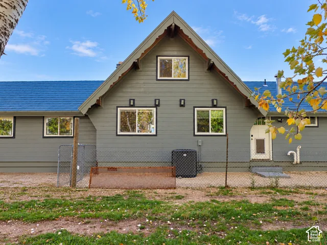 Gable-roof exterior featuring horizontal siding, decorative millwork, blue shingles, and fixed wall-mounted lighting